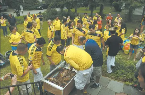  ?? DANA JENSEN/THE DAY ?? The roasting pig, for after the game, is checked at the Groton home of Yenny Vanegas and William Silva while family and friends gather outside during halftime Saturday of the Colombia vs. Greece World Cup soccer game. World Cup roundup in Sports, B3.