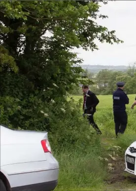  ??  ?? Local detectives and uniformed gardai gather at a field between Blackwater and Kilmuckrid­ge last Wednesday following the discovery of a shallow grave with human remains.