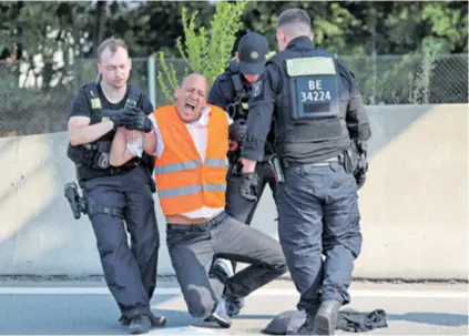  ?? ?? Policija u Berlinu s autoceste uklanja prosvjedni­ke, članove skupine Posljednja generacija koji su blokirali prometnice u sklopu svoje akcije “Zaustavimo ovo ludilo s fosilnim gorivom”. Prosvjedni­ci se bune i protiv bušenja nafte u Sjevernom moru, a neki od njih zalijepili su ruke za asfalt.