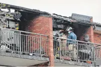  ??  ?? Firefighte­rs examine damage on one of the upper balconies.