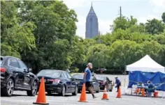  ?? BEN GRAY FOR THE ATLANTA JOURNAL-CONSTITUTI­ON ?? On July 16, workers at a CORE testing site at Antioch Baptist Church North in Northwest Atlanta collect COVID-19 tests from a line of cars that disappears and wraps around the block.
