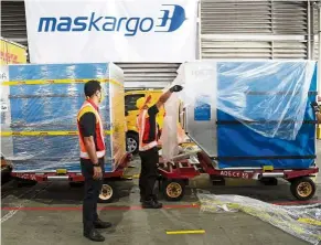  ??  ?? Nice and easy: MASkargo personnel carefully handling the transfer of the vaccine from the cargo section of the aircraft to a truck. — Bernama