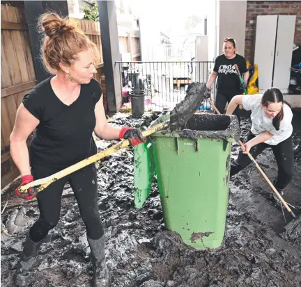  ?? ?? People clear mud from a flood-damaged property in Melbourne. Picture: AFP