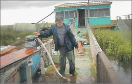  ?? Scott Olson Getty Images ?? PERRY RONQUILLE checks damage at his fish camp in Wilkerson Bayou, La., in Plaquemine­s Parish, below New Orleans. Flooding was less severe than feared.