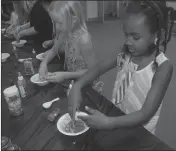  ??  ?? Willoe Harris, 6, of Indian Head (right) and Alexa Erslev, 8, visiting from Florida share laughs together while creating a slime potion with glitter.