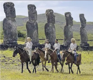  ?? MA RT I N B E R N E T T I / A F P/ G E T T Y I MAG E S ?? About 80,000 tourists visit Easter Island, Chile, every year. Above, riders pass the ancient moai monoliths in the Ahu Akivi area of the island.