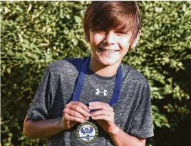  ?? Zach Dwyer / Associated Press ?? Kade Lovell holds his medal for winning the St. Francis Franny Flyer 10K in Sartell, Minn. He accidental­ly won after going the wrong way while competing in a 5K event. Kade, 9, started running with a cross country club at 6.