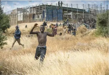  ?? JAVIER BERNARDO/AP ?? Migrants run on Spanish soil Friday after crossing fences separating the Spanish enclave of Melilla from Morocco in North Africa. Some 130 migrants breached the border, the first such incursion since the two countries mended diplomatic relations last month. A spokespers­on for the Spanish government said about 2,000 people tried to enter Melilla.