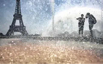  ?? | EPA ?? PEOPLE cool down at the fountains in Jardins du Trocadero, opposite the Eiffel Tower, during a heatwave in Paris, yesterday.