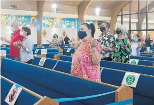  ?? PHOTOS BY JOE CAVARETTA/SOUTH FLORIDA SUN SENTINEL ?? Parishione­rs at St. Bernadette Catholic Church in Hollywood pray the Our Father during Mass on Sunday, the first day Catholic churches have returned to in-person Masses since March.