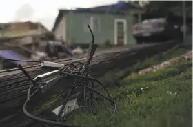  ?? Carlos Giusti / Associated Press ?? A utility pole knocked down by Hurricane Maria remains on the ground Dec. 22 in front of a home in Morovis, Puerto Rico. The storm struck on Sept. 20.