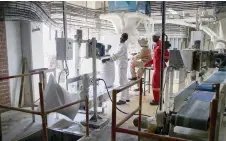  ?? ?? A worker wearing a dust mask packs bags of the maize meal staple at National Foods, a mealie meal processing and packaging company, in Harare.