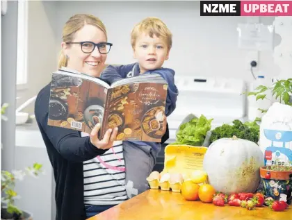  ?? Photo /Andrew Warner ?? Grounded in Goodness cookbooks are printed and ready for distributi­on. Emma Ward with son Alex, 2.