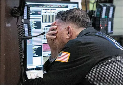  ?? AP/RICHARD DREW ?? Trader Jonathan Mueller works in his booth Friday on the floor of the New York Stock Exchange, where stocks took a beating after earnings reports disappoint­ed investors.