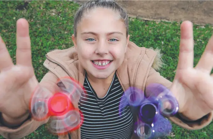  ??  ?? Nine-year-old Katie Bernard from Merrimac shows off her skills with her fidget spinners – the latest craze to hit the Gold Coast. Picture: GLENN HAMPSON