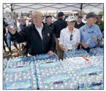  ?? AP/EVAN VUCCI ?? President Donald Trump and first lady Melania Trump hand out water Monday in Lynn Haven, Fla., during a visit to areas devastated by Hurricane Michael.