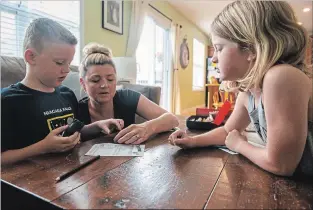  ?? ANDREJ IVANOV WATERLOO REGION RECORD ?? Kerri Gettliffe and her children, Brenden and Lauren Cooper, play Yahtzee at their home in Baden. Both children are in a French immersion program with the public board. Gettliffe feels that if the children have two languages, it may help them be more successful in their careers.