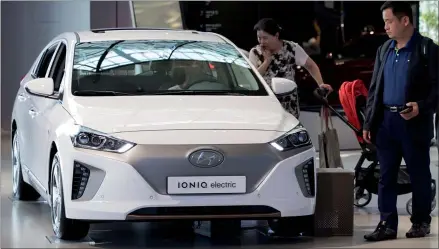 ?? SEONG JOON-CHO / BLOOMBERG ?? Visitors look at an Ioniq electric vehicle by Hyundai at the Hyundai Motorstudi­o showroom in Goyang, South Korea.