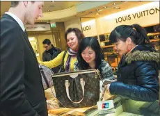  ?? JAMES MCCAULEY / HARRODS VIA GETTY IMAGES ?? Shoppers make a purchase using a UnionPay debit card at Harrods in London.