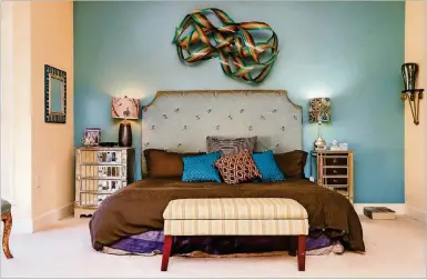  ?? ROGERS. TEXT BY SHANNON DOMINY. PHOTO BY REYNOLDS ?? Marcia Jaffe’s master bedroom is cool and more modern than the rest of her home, with a wooden ribbon sculpture by artist Renee Dinauer hanging above her bed. The accent wall behind the bed is painted Martha Stewart Hosta Green.