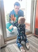  ?? ALYSSA BURKS ?? Dr. Jared Burks sees his son, Zeke, 1, crawl for the first time on March 25. The two were separated by a glass door at their Jonesboro, Ark., home. Three days after the photo was posted, the family's house was destroyed by a tornado.