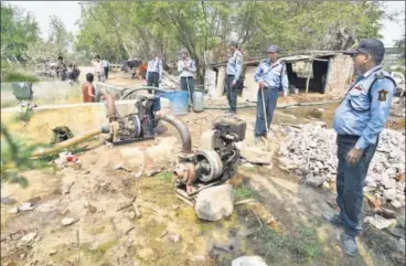  ?? SANCHIT KHANNA/HT PHOTOS ?? Private guards (above) hired by the DDA at an illegal bore well in the Yamuna floodplain at Chilla Khadar, where debris has also been dumped. Indiscrimi­nate dumping of debris is choking the river flow, say officials and experts. (Left) Cars parked on...