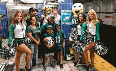  ?? Matt Liston / Associated Press ?? Philadelph­ia Eagles fan Jigar Desai, center, poses with his family, friends and members of the Philadelph­ia Eagles Cheerleade­rs in front of the subway pillar he ran into in January, spurring a viral video.