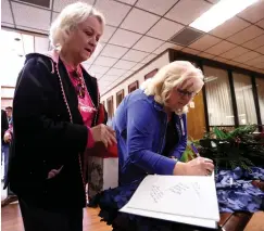  ?? Staff photo by Hunt Mercier ?? ■ Valerie Owen looks for a place to sign her name Tuesday while Pam Owney writes hers in the farewell book that will be given to James Henry Russell, the outgoing president of Texarkana College.