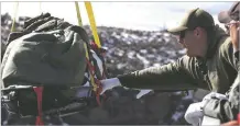  ?? JOHN MILLER/TAOS NEWS ?? A Taos County sheriff’s deputy grabs a basket carrying the body of a man who died at the Rio Grande Gorge Bridge sometime in early January.