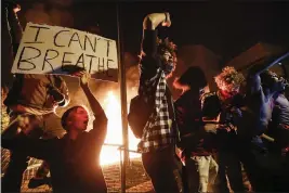  ?? JOHN MINCHILLO — THE ASSOCIATED PRESS ?? Protesters demonstrat­e outside of a burning Minneapoli­s 3rd Police Precinct on Thursday in Minneapoli­s.