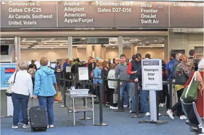  ?? MICHAEL SEARS / MILWAUKEE JOURNAL SENTINEL ?? People wait in line Wednesday to go through security to board their flights at Mitchell Internatio­nal Airport in Milwaukee.