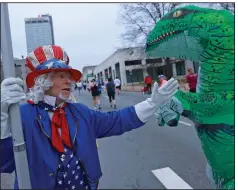  ?? (Arkansas Democrat-Gazette/Colin Murphey) ?? Marvin Fisher of Sherwood, dressed as Uncle Sam, high-fives a runner dressed in a dinosaur costume Sunday in the 22nd annual Little Rock Marathon.