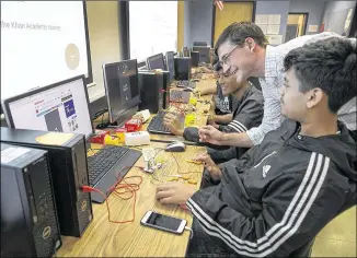  ?? RALPH BARRERA / AMERICAN-STATESMAN ?? Reagan High School teacher Eric Shaffer assists students Elton Torres (right) and Alejandro Fernandez (left) with their assignment — programmin­g a Play-Doh joystick — in an Introducti­on to Engineerin­g class for freshmen that will help the students...