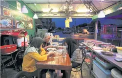  ??  ?? LEFT
A Muslim family break their fast at the end of the day inside their restaurant in Selayang, Malaysia.