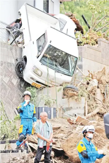  ??  ?? A family member of missing people watches search and rescue operations at a landslide site caused by a heavy rain in Kumano Town, Hiroshima Prefecture, western Japan. — Reuters photo