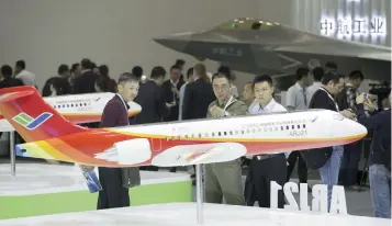  ?? — Reuters ?? Visitors look at a model of the ARJ21 regional jet at the Aviation Expo China 2015 in Beijing.