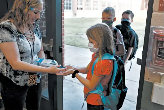  ?? LM OTERO/AP ?? Students use hand sanitizer before entering school Wednesday in Godley, Texas.