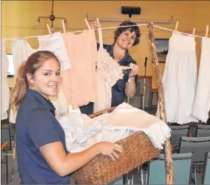  ?? ERIC MCCARTHY/JOURNAL PIONEER ?? Alberton Visitor Informatio­n Centre guide Dena McHugh, foreground, helps co-worker Isabel Delaney load a clotheslin­e with a display of women’s undergarme­nts from the 1800s. They were brought out of storage at the Alberton Museum for the special display.