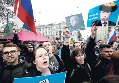  ??  ?? Demonstrat­ors carry posters criticisin­g President Vladimir Putin during a massive protest rally in St Petersburg, Russia, yesterday.