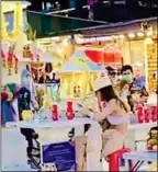  ?? Image: supplied via Eakkapop Thongtub ?? A Thai visitor to the market waits to pay her respects at the shrine while a young female tourist sits at the altar preoccupie­d with her mobile phone.