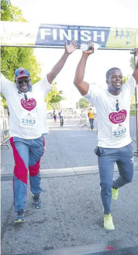  ??  ?? 2017/18 LASCO/MOEYI Principal of the Year Howard Salmon (left) and 2018/19 LASCO Top Cop Constable Davian Martin celebrate as they cross the finish line at the first staging of the Civil Service Week 5K.