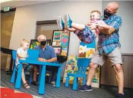  ?? JARROD VALLIERE U-T ?? Dave Walker sits with Grayson Magnuson, 4, while brother William, 3, is swung by their father Bob Magnuson. The Walkers’ gift funds 2,780 hours of respite care.