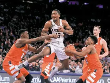  ?? Jason DeCrow/Associated Press ?? Connecticu­t's Rodney Purvis is stripped of the ball by Syracuse's John Gillon Monday in a game at Madison Square Garden in New York. Connecticu­t won, 52-50.