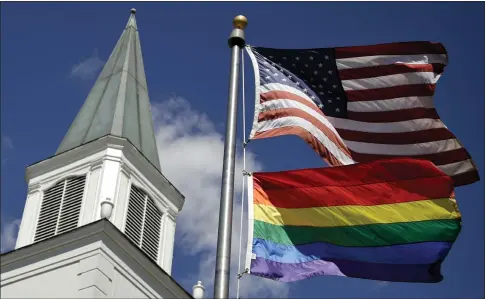  ?? CHARLIE RIEDEL, FILE — THE ASSOCIATED PRESS ?? A gay pride rainbow flag flies along with the U.S. flag in front of the Asbury United Methodist Church in Prairie Village, Kan., in 2019.