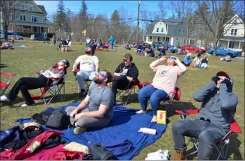  ?? PETER CURRIER — LOWELL SUN ?? From left: Rebecca Doolan, Max Yelle, Sean Duggan, Maciej Jachtorowi­cz, Caitlin Duncan and Evan Zuckerman don their eclipse glasses as the moon begins its transit of the sun during the Aug. 8, 2024solar eclipse as they sit on the green of the Vermont College of Fine Arts in Montpelier, Vermont.
