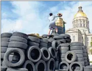  ?? Contribute­d by Joe Cook, File ?? Activists with the Georgia Water Coalition top off the “Scrapitol,” a replica of the state Capitol constructe­d from scrap tires, during a rally in March 2017 at the Capitol. The rally brought attention to the Hazardous Waste and Solid Waste Trust Funds diverted by state budget writers.