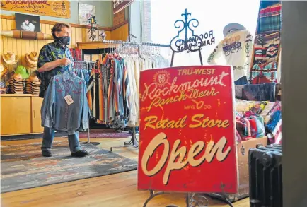  ?? Hyoung Chang, The Denver Post ?? Steve Weil, owner of Rockmount Ranch Wear, prepares Friday for the reopening of the store in downtown Denver.
