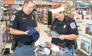  ?? / Doug Walker ?? Floyd County police Sgt. Chris Fincher (left) checks some of the items officer Ginger Shelly has picked out for an autistic child who was not able to be present Saturday.