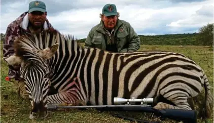  ?? ?? Shocking sight: Colin Brooks, from March in Cambridges­hire, is a retired businessma­n who delights in his bloody pastime. He’s pictured here on the right with a freshly killed zebra, and on his Facebook profile posing with a dead warthog under an image of a shot cartridge