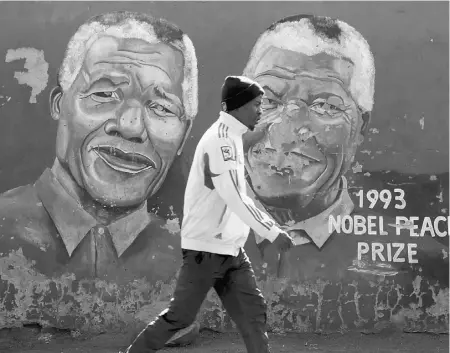  ?? Chip Somodevill­a/ Getty Images ?? A man walks past a mural depicting former South African president Nelson Mandela in Soweto Township.